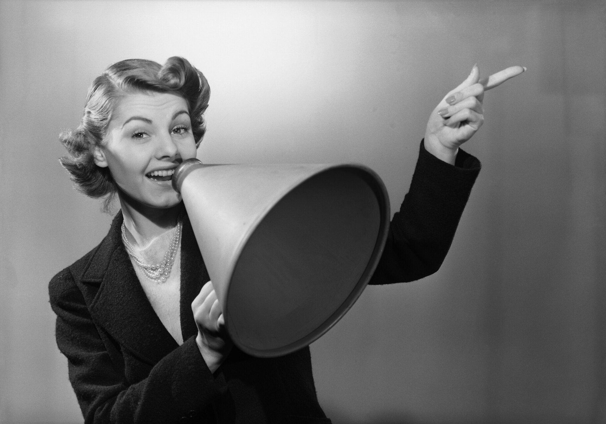 A happy woman, holding a megaphone, making an announcement.